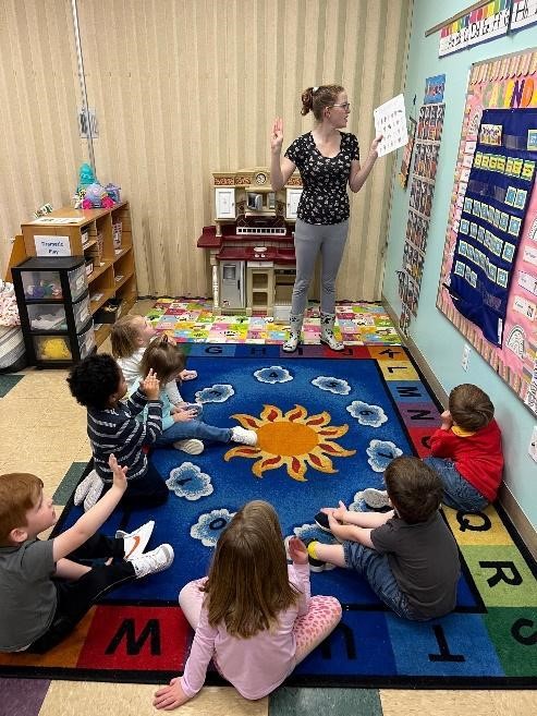 children around a teacher showing ASL