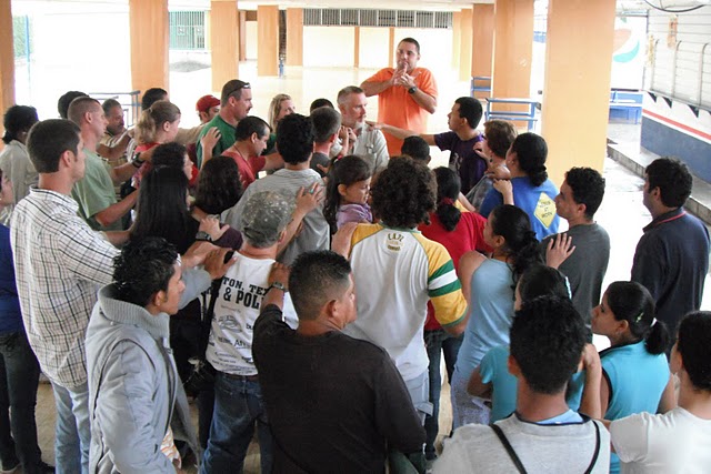 New Life Deaf Church, and Lovers Lane Deaf Honduras Mission team prays for Andy Bugh, missionary for New Life Deaf Ministry, for safety and success on his 4,000 mile kayaking fundraiser for NLDM on the Missouri and Mississippi Rivers.  Melvin Lazo, (standing, orange shirt) pastor of NLDM is praying. Andy is below Melvin. Photo taken in Tegucigalpa.