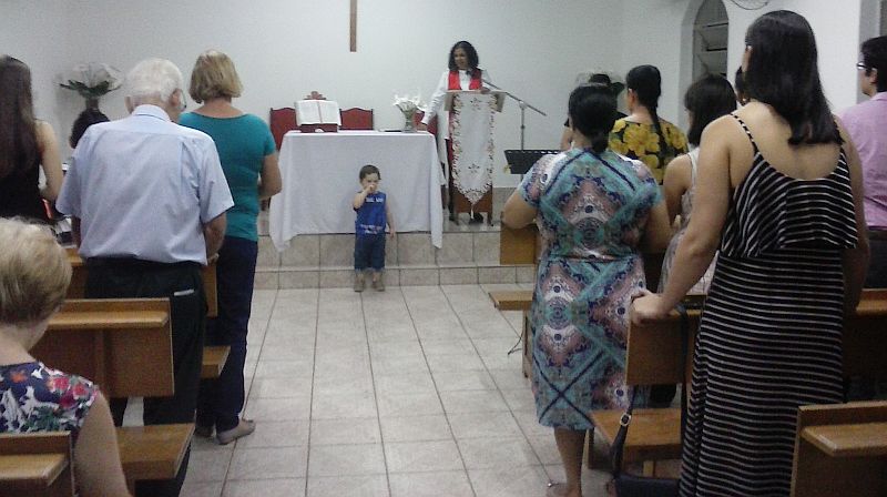 the author leads a worship service from a pulpit, people in pews are standing, and a child is in front making signs.